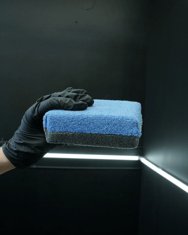 A person with black gloves holding a extra large no soak ceramic coating applicator