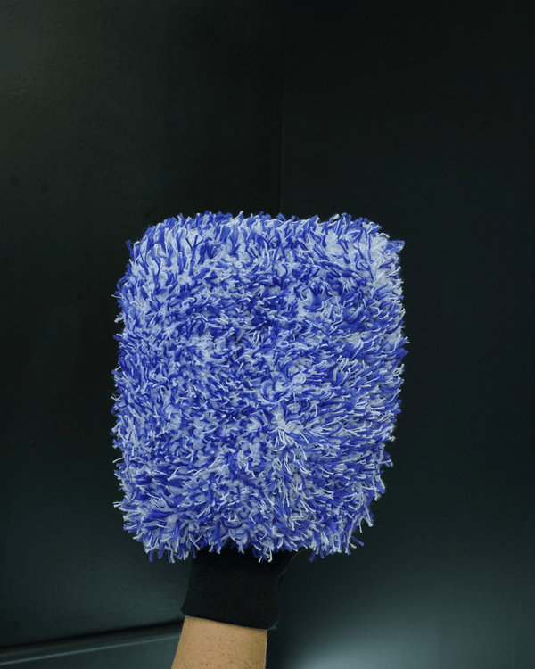 A detailer holding a blue and white premium microfibre wash mitt on a lack background
