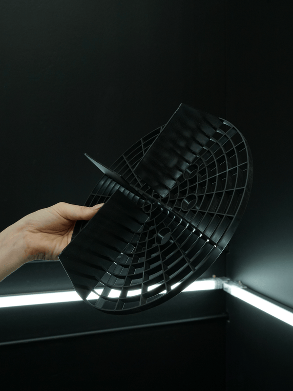 Hand holding a round metal grid against a dark background