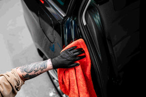 Professional detailer drying black car door jamb with orange Double Mini Twisted Towel