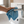 A person using a blue microfibre cloth to clean a bathroom sink in a modern bathroom
