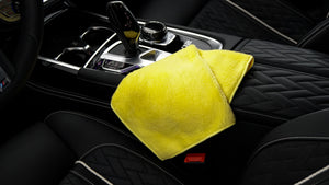 A yellow microfibre cloth folded in a black leather car interior 