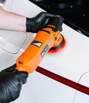 A detailer using a ADBL roller DA 15125 polishing machine to polish a white car