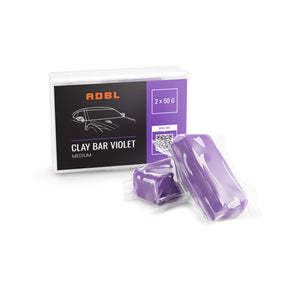 A box with a black label a two purple clay bars on a white background
