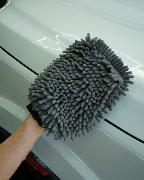 A detailer washing a white car with a grey noodle sponge