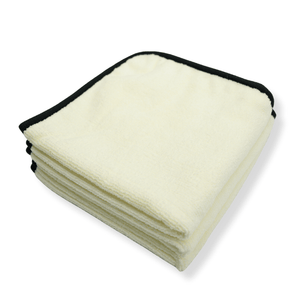 A stack of folded plush white microfibre towels with a black border on a white background