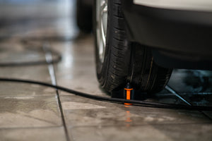 ADBL SNAKECHARMER Functional Hose Chock in use next to a car tire keeping the hose clear