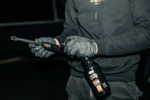 Person in black gloves spraying interior cleaner onto a DETAILING BRUSH PRO for car interior cleaning
