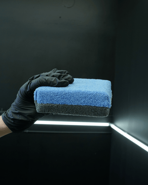 A person with black gloves holding a extra large no soak ceramic coating applicator
