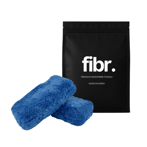 A black bag with FIBR written on it next to 2 blue plush sponge applicators