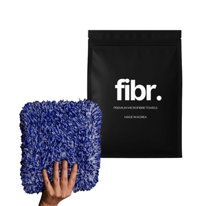 A black bag with FIBR written on it next to a hand holding a large blue and white microfibre wash pad