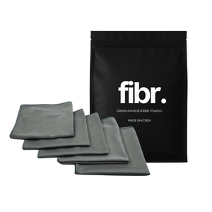 A black bag with FIBR written on it next to a stack of korean glass cloths