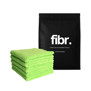A black bag with FIBR written on it next to a plush dual pile microfibre cloth stack