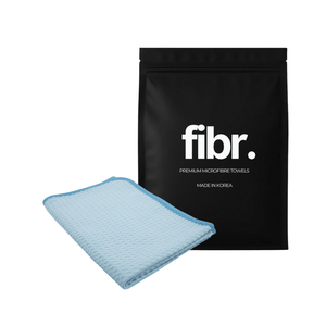 A black FIBR bag next to a blue waffle weave microfibre cloth