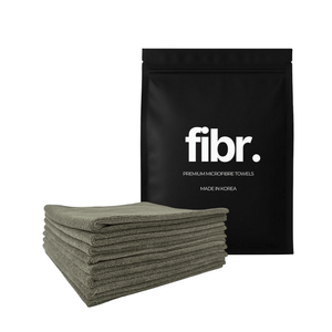 A black bag with FIBR written on it next to a low nap grey microfibre cloth stack