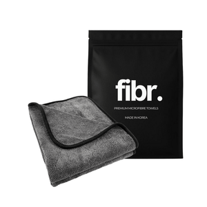 A black bag with FIBR written on it next to a grey microfibre drying towel