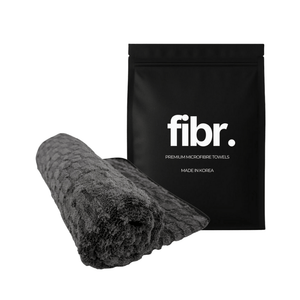 A black bag with FIBR written on it next to a grey microfibre drying towel