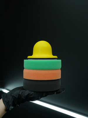 Stack of colourful foam blocks held by a gloved hand against a dark background