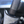 A person with a black glove on holding a car interior scrub sponge cleaning a steering wheel