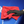 Person cleaning a blue car with a red microfibre and black glove