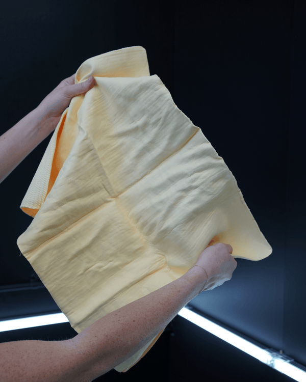 A person holding a yellow chamois on a black background