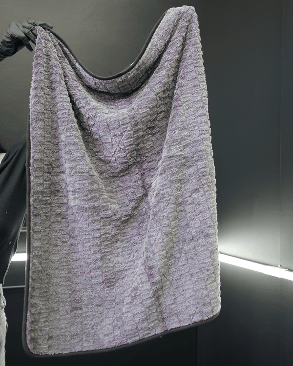 A person holding a large grey microfibre drying towel