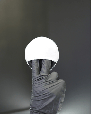 A detailer wearing black gloves with a small white applicator