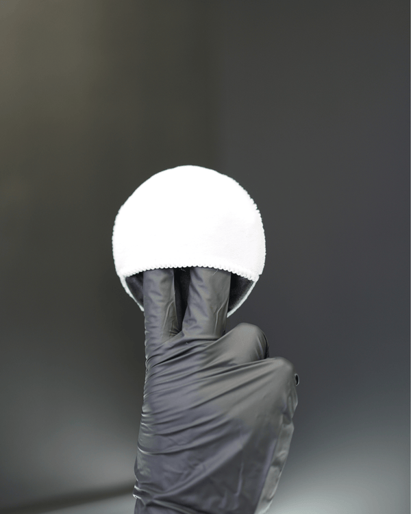 A detailer wearing black gloves with a small white applicator