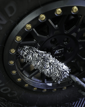 A black and white wheel woolie brush cleaning a black wheel 