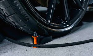 Close-up of ADBL SNAKECHARMER Functional Hose Chock preventing hose from getting stuck under a car tire