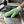 A green cleaning glove being used on a stainless stovetop to remove grime off the surface