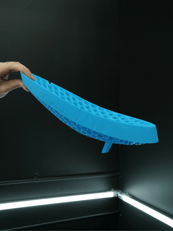 Hand holding a blue curved grit guard for a car wash bucket