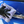 Person cleaning a blue car door handle with a purple microfibre cloth and black gloves.
